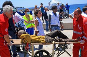 مسعفون من الصليب الأحمر الإيطالي يعالجون عاملاً مهاجراً مصاباً في ميناء لامبيدوسا -ايرين